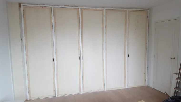 Afgewerkte kamerbrede kastenwand met vijf hoge deuren