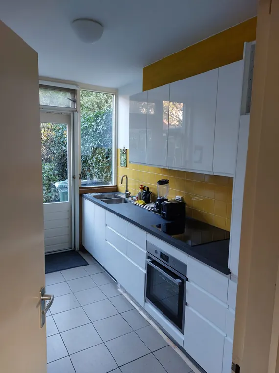 Keuken na de renovatie, met witte hoogglans fronten en een strakke afwerking