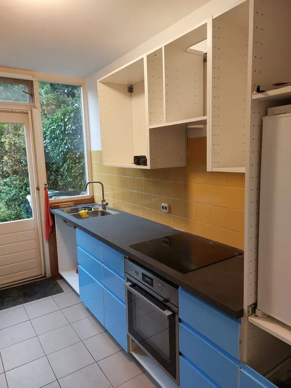 Keuken voor de renovatie, met open bovenkasten en blauwe ladefronten