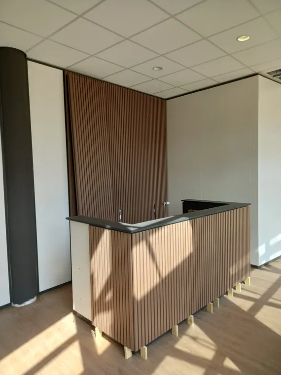 Receptiebalie en hoge wand met warme houten latten